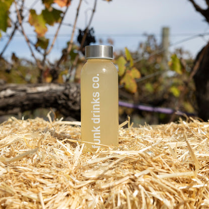 Funk Drinks Co Ginger Tonic cold pressed juice bottle on a straw bale beside a grapevine