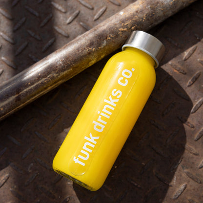 Funk Drinks Co orange juice bottle lying on a rusted metal tread plate
