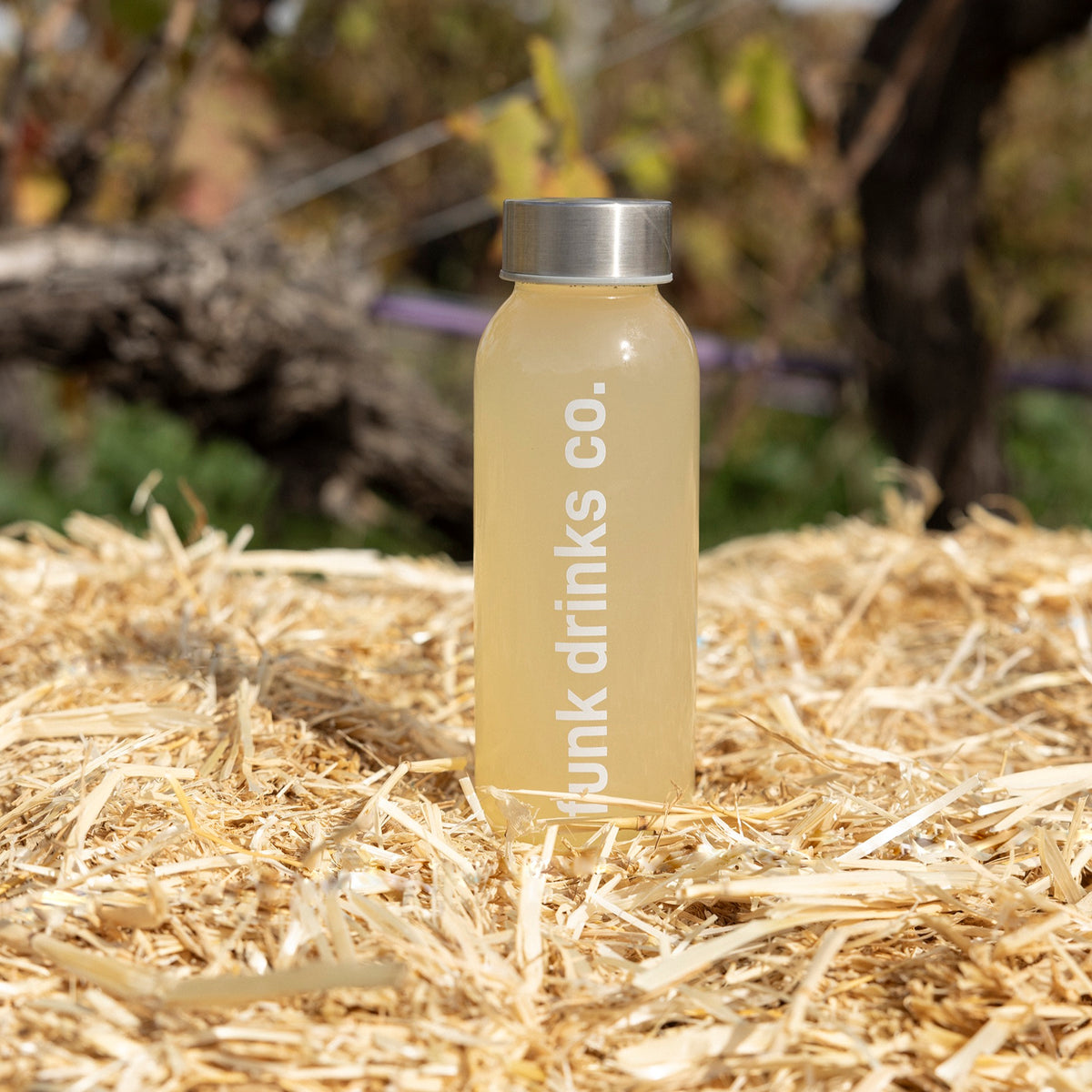 A bottle of Funk Ginger Tonic cold pressed juice on a straw bale in the vineyard