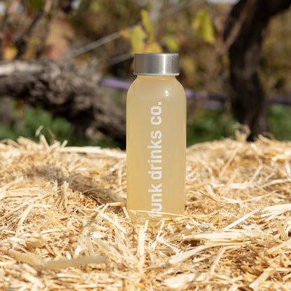 A bottle of Funk Ginger Tonic cold pressed juice on a straw bale in the vineyard